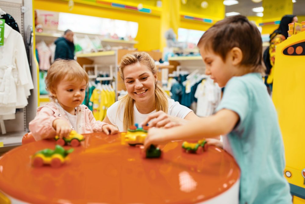 Mother with little children playing in kids store