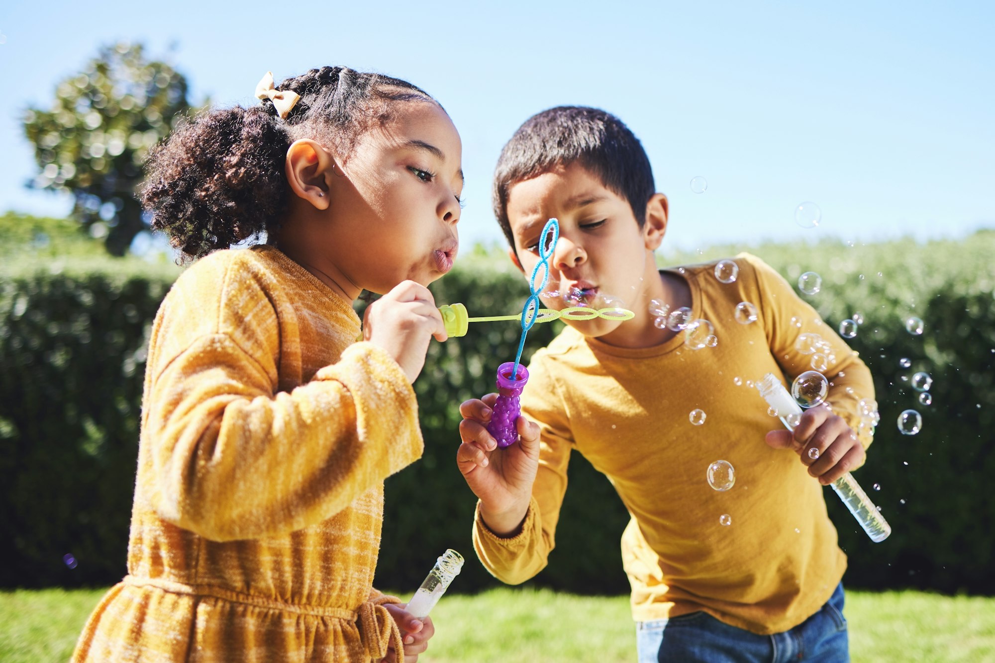Playing, garden and children blowing bubbles for entertainment, weekend activity and fun together.