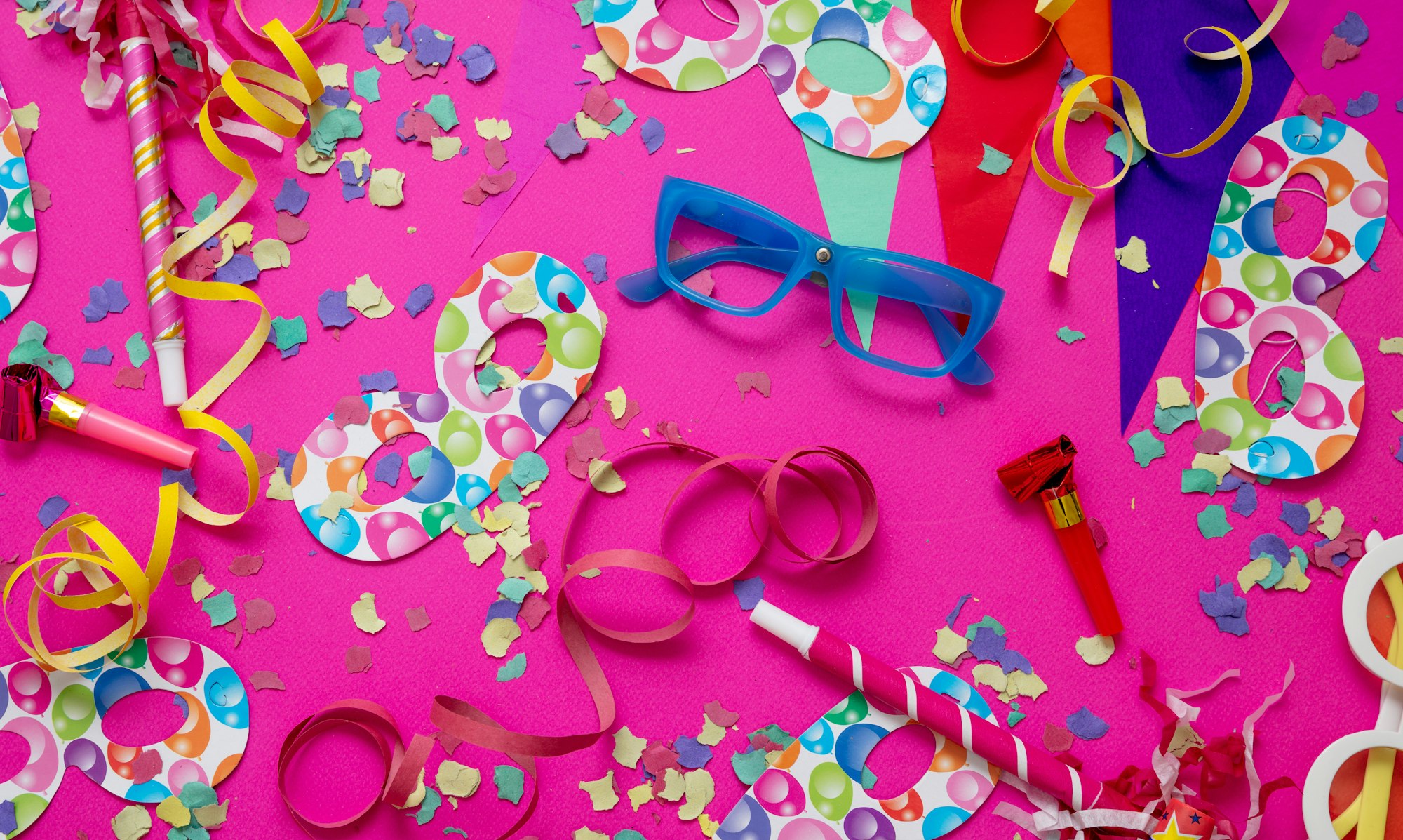 Carnival birthday party. Confetti and serpentines on bright pink background, overhead view